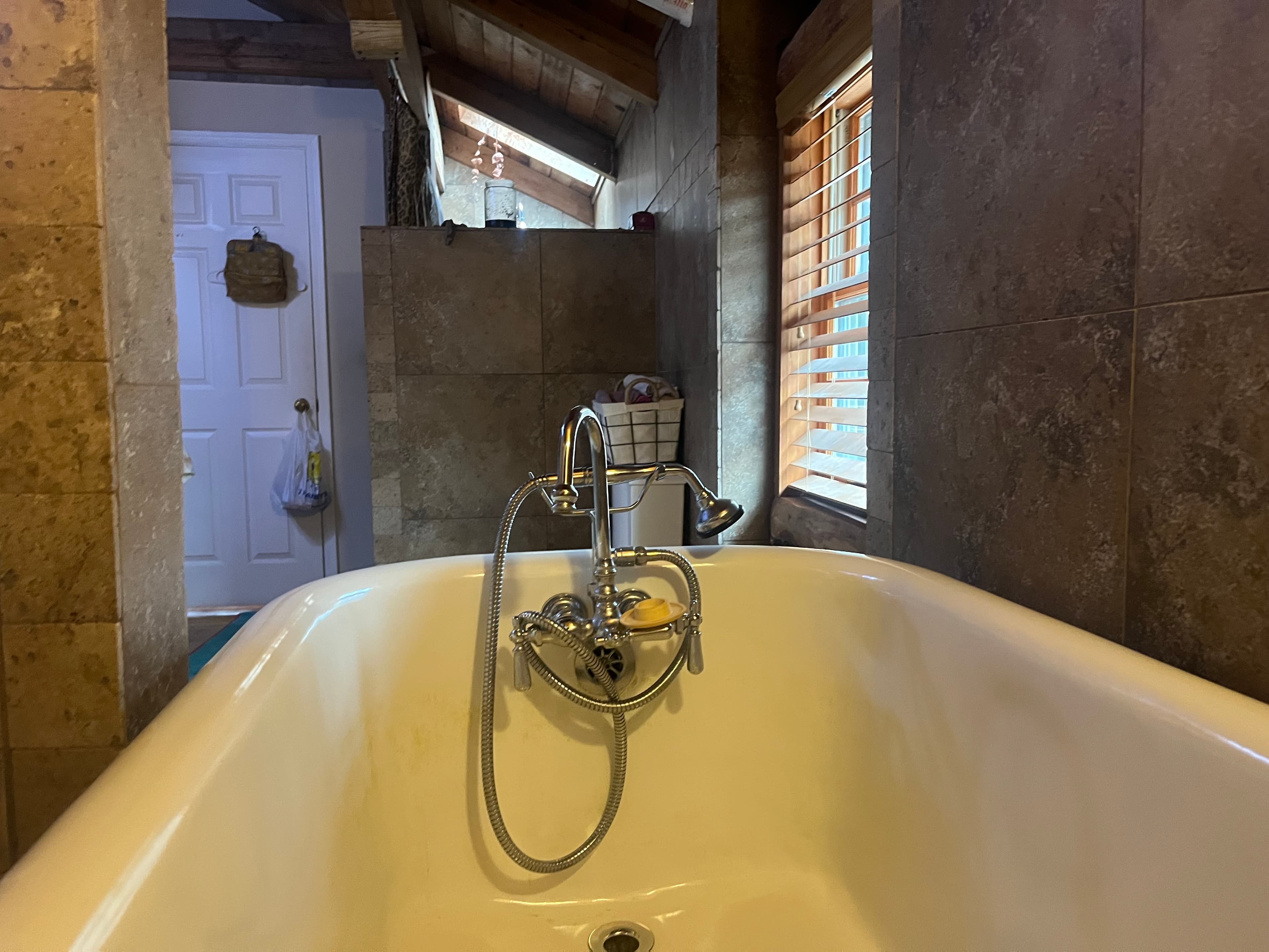 Clawfoot tub with exposed beams and skylight